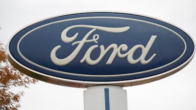 In this Oct. 20, 2019, file photo, the company logo stands over a long row of unsold vehicles at a Ford dealership in Littleton, Colo.