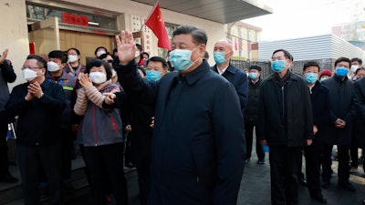In this photo released by Xinhua News Agency, Chinese President Xi Jinping, centre, wearing a protective face mask waves as he inspects the novel coronavirus pneumonia prevention and control work at a neighbourhoods in Beijing on Monday, Feb. 10. China reported a rise in new virus cases on Monday, possibly denting optimism that its disease control measures like isolating major cities might be working, while Japan reported dozens of new cases aboard a quarantined cruise ship.