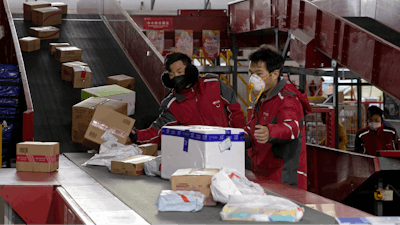 In this Tuesday, Feb. 18, 2020, photo, delivery workers for Chinese e-commerce giant JD.com sort out parcels at a distribution center in Beijing, China.