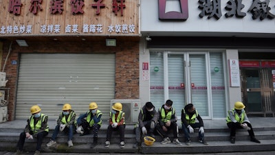 Workers take a rest near the closed restaurant and bank in Wuhan in central China's Hubei province.
