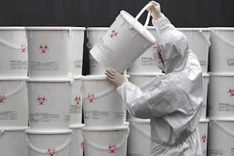 A worker in protective gear stacks plastic buckets containing medical waste from coronavirus patients at a medical center in Daegu, South Korea on Monday, Feb. 24. South Korea reported another large jump in new virus cases Monday a day after the the president called for 'unprecedented, powerful' steps to combat the outbreak that is increasingly confounding attempts to stop the spread.