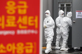 Officials wearing protective attire work to diagnose people with suspected symptoms of the new coronavirus at a hospital in Daegu, South Korea on Wednesday, Feb. 26. The number of new virus infections in South Korea jumped again Wednesday and the U.S. military reported its first case among its soldiers based in the Asian country, with his case and many others connected to a southeastern city with an illness cluster. A sign reads 'Emergency Medical Center.'