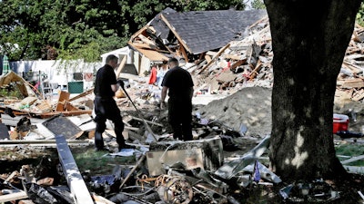 In this Sep. 21, 2018, file photo, fire investigators pause while searching the debris at a home which exploded following a gas line failure in Lawrence, Mass.