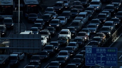 In this Dec. 11, 2018, file photo, a beam of sunlight is cast on vehicles on a city ring-road clogged with heavy traffic during the morning rush hour in Beijing, China. Auto sales in China have plunged, deepening a painful downturn in the industry’s biggest global market and adding to economic pressure as the country fights a virus outbreak.