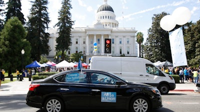 In this Aug. 28, 2019 file photo supporters of a measure to limit when companies can label workers as independent contractors circle the Capitol during a rally in Sacramento, Calif. U.S. District Judge Dolly Gee denied a request by ride-share company Uber and on-demand a request delivery service Postmates for a preliminary injunction protecting them from the new law aimed at giving protections to people who work as independent contractors, Monday, Feb.10, 2020.