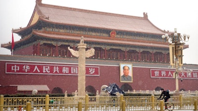 A man wears a face mask as he rides a bicycle past Tiananmen Gate near Tiananmen Square during a snowfall in Beijing, Wednesday, Feb. 5, 2020. Deaths from a new virus rose to 490 in mainland China on Wednesday while new cases on a Japanese cruise ship, in Hong Kong and in other places showed the increasing spread of the outbreak and renewed attention toward containing it.