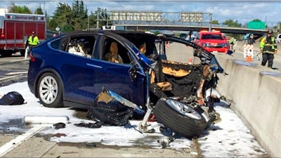 In this March 23, 2018, file photo provided by KTVU, emergency personnel work a the scene where a Tesla electric SUV crashed into a barrier on U.S. Highway 101 in Mountain View, Calif. The National Transportation Safety Board says the driver of a Tesla SUV who died in a Silicon Valley crash two years ago was playing a video game on his smartphone at the time. Chairman Robert Sumwalt said at the start of a hearing Tuesday, Feb. 25, 2020 that partially automated driving systems like Tesla's Autopilot cannot drive themselves. Yet he says drivers continue to use them without paying attention.