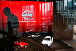 In this July 25, 2019, file photo, a man rides an escalator as Nissan vehicles are showcased in the Nissan Gallery in Yokohama, west of Tokyo. Nissan, reeling from a scandal over its former superstar executive Carlos Ghosn, sank into red ink in the latest quarter as its vehicle sales fell around the world, and the Japanese automaker slashed its profit forecast for the year.
