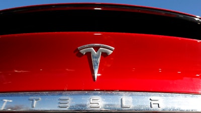 In this Feb. 2, 2020 file photograph, the company logo sits on an unsold 2020 Model X at a Tesla dealership in Littleton, Colo. Shares of Tesla Inc. fell 4% in early trading Thursday, Feb. 13, after the electric vehicle and solar panel maker said it would sell more than $2 billion worth of additional shares. The move comes just two weeks after CEO Elon Musk said the company had enough cash to fund its capital programs and it didn't need to raise any more money.
