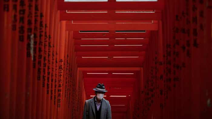 A man with a mask walk through torii gates at the Hie Shrine In Tokyo, Sunday, March 1, 2020.