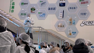 In this Thursday, Feb. 27 photo, journalists dressed in protective overalls visit the Mengniu dairy factory in Beijing. Reporters were invited to China Mengniu Dairy Co. Ltd. last week to be shown how companies are reviving after anti-virus measures shut down most of the world's second-biggest economy.