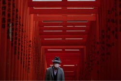 A man with a mask walk through torii gates at the Hie Shrine In Tokyo, Sunday, March 1, 2020.