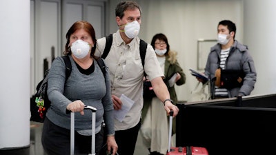 Travelers wear protective masks as they walk through in terminal 5 at O'Hare International Airport in Chicago on Sunday, March 1.