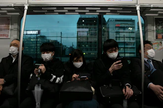 Commuters wearing masks sit on a train in Tokyo on Monday, March 2. Coronavirus has spread to more than 60 countries, and more than 3,000 people have died from the COVID-19 illness it causes.