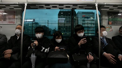 Commuters wearing masks sit on a train in Tokyo on Monday, March 2. Coronavirus has spread to more than 60 countries, and more than 3,000 people have died from the COVID-19 illness it causes.