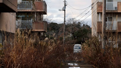 In this Dec. 3, 2019, file photo, weeds grow in an abandoned apartment complex, in Futaba, Fukushima prefecture, Japan.