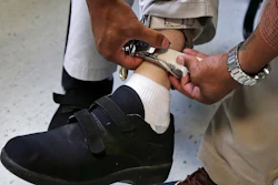 In this Aug. 13, 2014 file photo, a therapist checks the ankle strap of an electrical shocking device on a student during an exercise program at the Judge Rotenberg Educational Center in Canton, Mass.