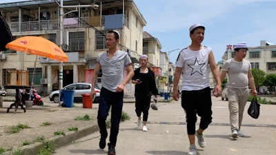 In this June 5, 2019, photo, residents of the Hui Muslim ethnic minority walk in a neighborhood near an OFILM factory in Nanchang in eastern China's Jiangxi province.