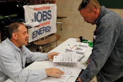 In this Nov. 2, 2017, photo, a recruiter in the shale gas industry, left, speaks with an attendee of a job fair in Cheswick, Pa.