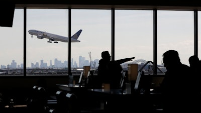 In this July 18, 2018, file photo, a United Airlines commercial jet takes off as travelers sit at a gate in Terminal C of Newark Liberty International Airport in Newark, N.J.