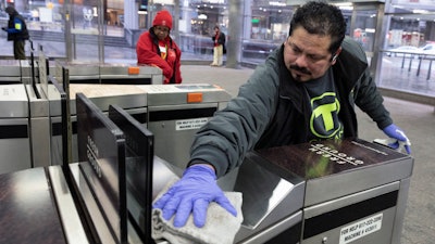 In this March 13 photo, a worker disinfects a turnstile at the Government Center transit stop, in Boston. As the global viral pandemic grows, the need for cleaning and disinfecting has surged. Cleaners and domestic workers are essential in the effort to contain the virus.