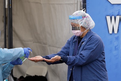 In this March 17, 2020, photo, Theresa Malijan, a registered nurse, has hand sanitizer applied on her hands.