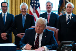 In this March 27, 2020 file photo, President Donald Trump signs the coronavirus stimulus relief package in the Oval Office at the White House.
