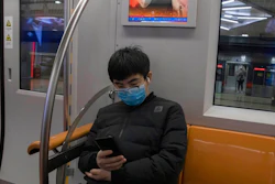 A passenger sits under a public information display encouraging the use of mask on a subway train in Beijing Monday, March 9, 2020. With almost no new COVID-19 cases being reported in Beijing, workers are slowly returning to their offices with masks on and disinfectant in hand. But officials remain cautious, torn between wanting to restart the economy and fear of a resurgence of the outbreak.
