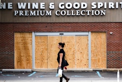 A pedestrian walks past a boarded up Wine and Spirits store in Philadelphia on Friday, March 20. Pennsylvania Gov. Tom Wolf directed all 'non-life-sustaining' businesses to close their physical locations late Thursday and said state government would begin to enforce the edict starting early Saturday.