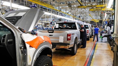 In this Sept. 27, 2018, file photo a United Auto Workers assemblymen work on a 2018 Ford F-150 trucks being assembled at the Ford Rouge assembly plant in Dearborn, Mich.