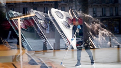 In this March 15, 2020 file photo, a worker cleans the Apple Store on the Champs-Elysees avenue in Paris. French regulators fined Apple 1.1 billion euros ($1.2 billion) on Monday March 16, 2020 for striking deals to keep prices high, in the biggest-ever such sanction by France's Competition Authority.