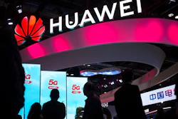 In this Oct. 31, 2019, file photo, attendees walk past a display for 5G services from Chinese technology firm Huawei at the PT Expo in Beijing. Chinese tech giant Huawei says its 2019 sales rose 19.1% over a year earlier despite U.S. sanctions that hampered its smartphone and network equipment businesses.