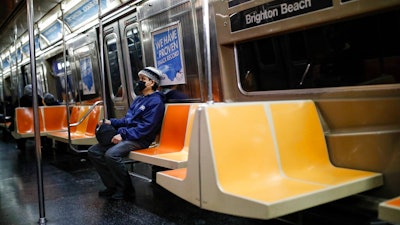 A commuter wears a face mask while riding the a nearly empty subway car into Brooklyn, Thursday, March 12, 2020, in New York. New York City Mayor Bill de Blasio said Thursday he will announce new restrictions on gatherings to halt the spread of the new coronavirus in the coming days, but he hopes to avoid closing all public events such as Broadway shows. For most people, the new coronavirus causes only mild or moderate symptoms. For some it can cause more severe illness.