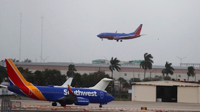 In this Jan. 10, 2020 file photo, a commercial plane flies into a windy, cloudy sky at the Fort Lauderdale-Hollywood International Airport in Fort Lauderdale, Fla. Federal regulators are temporarily waiving a rule that has been causing airlines to fly nearly empty planes to avoid losing precious takeoff and landing rights at major airports. On Wednesday, March 11, the FAA said it was waiving the 80% rule through May 31 to help airlines that are canceling flights because of the coronavirus outbreak.