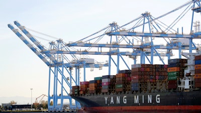 In this Nov. 4, 2019 file photo cargo cranes are used to take containers off of a Yang Ming Marine Transport Corporation boat at the Port of Tacoma in Tacoma, Wash.