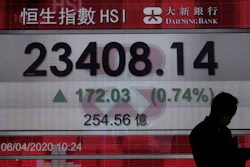 A man wearing face mask walks past a bank electronic board showing the Hong Kong share index in Hong Kong, Monday, April 6, 2020.