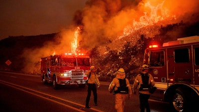In this Nov. 26, 2019, file photo, firefighters battle the Cave Fire as it flares up along Highway 154 in the Los Padres National Forest above Santa Barbara, Calif.
