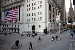 In this March 18 file photo, a few people walk on Wall Street in front of the New York Stock Exchange in New York. There are emerging signs that any recovery will fail to match the speed and severity of the economic collapse that occurred in just a few weeks.