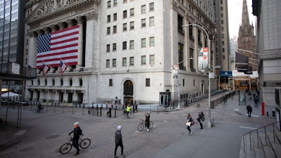 In this March 18 file photo, a few people walk on Wall Street in front of the New York Stock Exchange in New York. There are emerging signs that any recovery will fail to match the speed and severity of the economic collapse that occurred in just a few weeks.