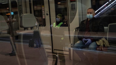 Commuters wearing face masks to protect against coronavirus at Atocha train station in Madrid, Spain, Monday, April 13, 2020.