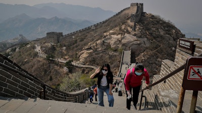 Women wearing protective face masks to prevent the spread of the new coronavirus walk on a stretch of the Badaling Great Wall of China in Beijing, Tuesday, April 14, 2020.