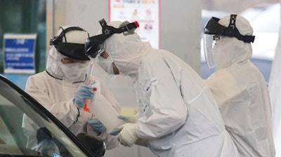 In this March 1, 2020 file photo, medical staff wearing protective suits take samples from a person with suspected symptoms of the new coronavirus at a drive-thru virus test facility in Goyang, South Korea. When the first cases of the disease showed up in South Korea, they reacted quickly with the use of widespread testing, technology to trace at-risk groups, and strict social quarantines and distancing.