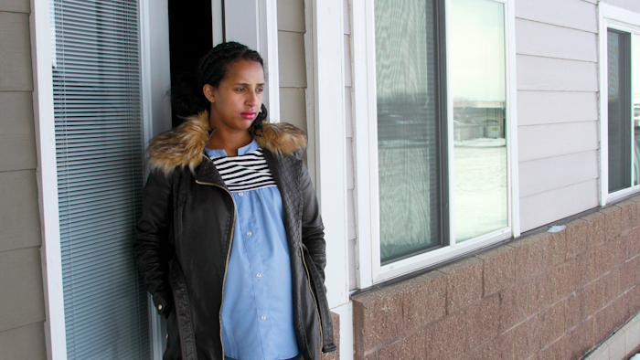 In this April 13, 2020, photo, Kulule Amosa steps out of the apartment she shares with her husband who works at the Smithfield Foods pork processing plant in Sioux Falls, S.D.