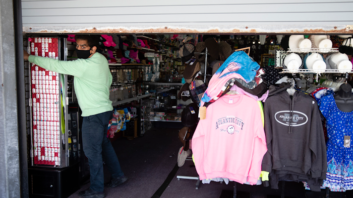 Mohammad Ikram closes a large door to his business Hot Stop, fully stocked but closed during the coronavirus pandemic.