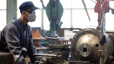 An employee wears a facemask as he works at a blower and fan manufacturing plant.