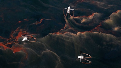 In this May 5, 2010 file photo, shrimp boats are used to collect oil with booms in the waters of Chandeleur Sound, La.