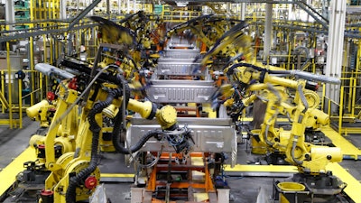 In this Sept. 27, 2018 file photo, robots weld the bed of a 2018 Ford F-150 truck on the assembly line at the Ford Rouge assembly plant in Dearborn, MI. US businesses are edging their way toward figuring out how to bring their employees back to work amid the coronavirus pandemic, some more gracefully than others. Detroit-area automakers, which suspended production in March, are now pushing to restart factories as soon as possible.