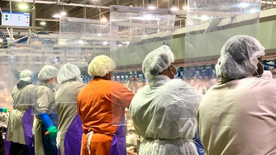 Tyson Foods workers wear protective masks and stand between plastic dividers at the company's Camilla, Georgia poultry processing plant.