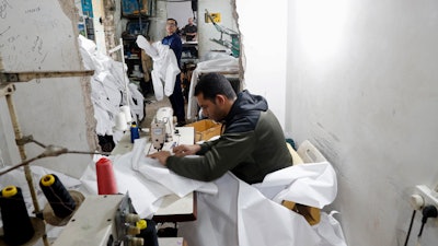 In this Monday, March 30, 2020 file photo, Palestinians make protective overalls meant to shield people from the coronavirus, to be exported to Israel, at a local factory, in Gaza City.