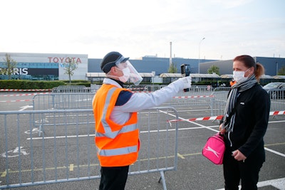 An employee has her temperature taken at the Toyota car factory in Onnaing, northern France, Monday, April 27, 2020.